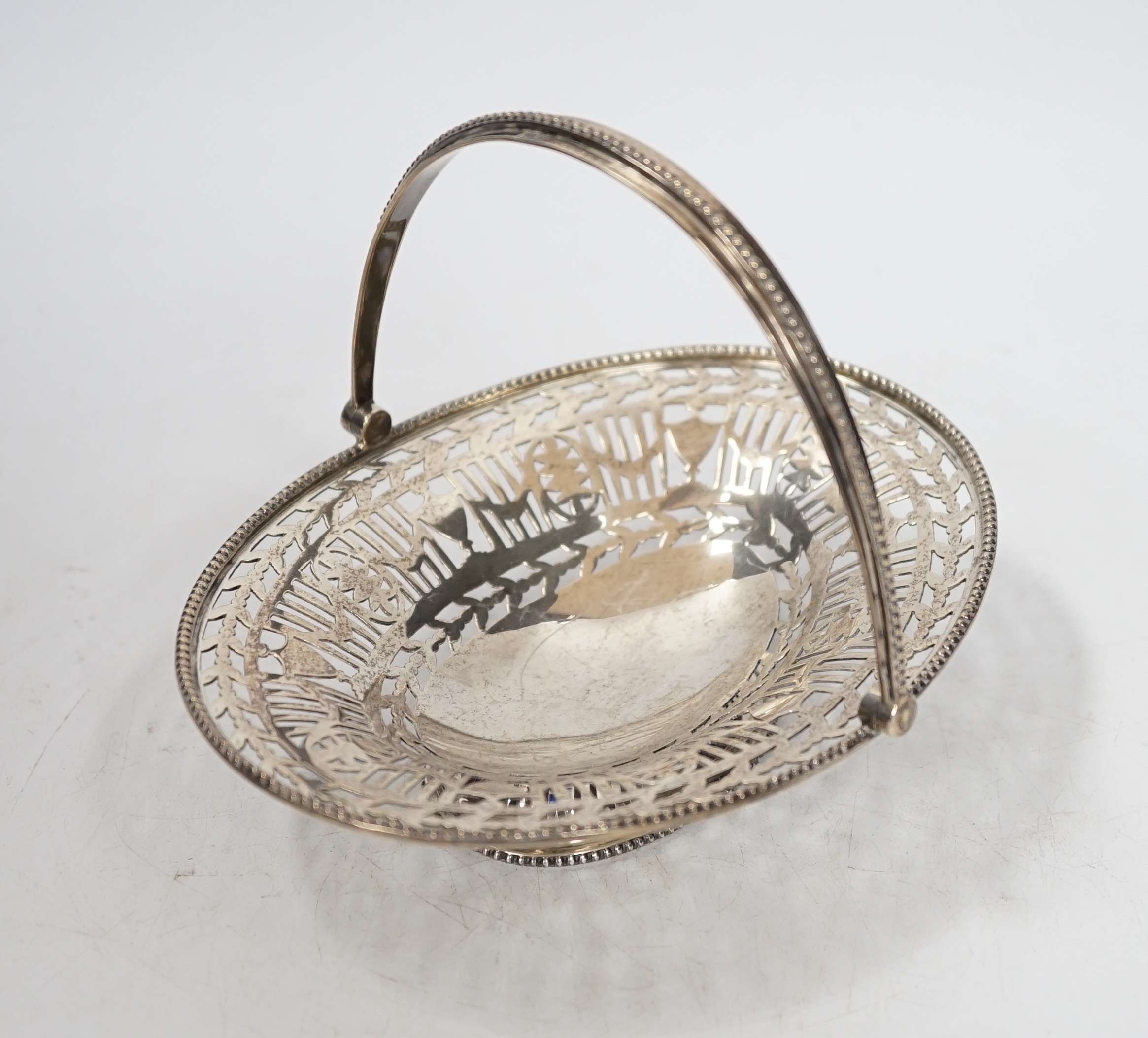 A George V pierced silver oval sweetmeat dish, with swing handle and fretwork decoration, Goldsmiths & Silversmiths Co., London 1912, 16cm, 174 grams